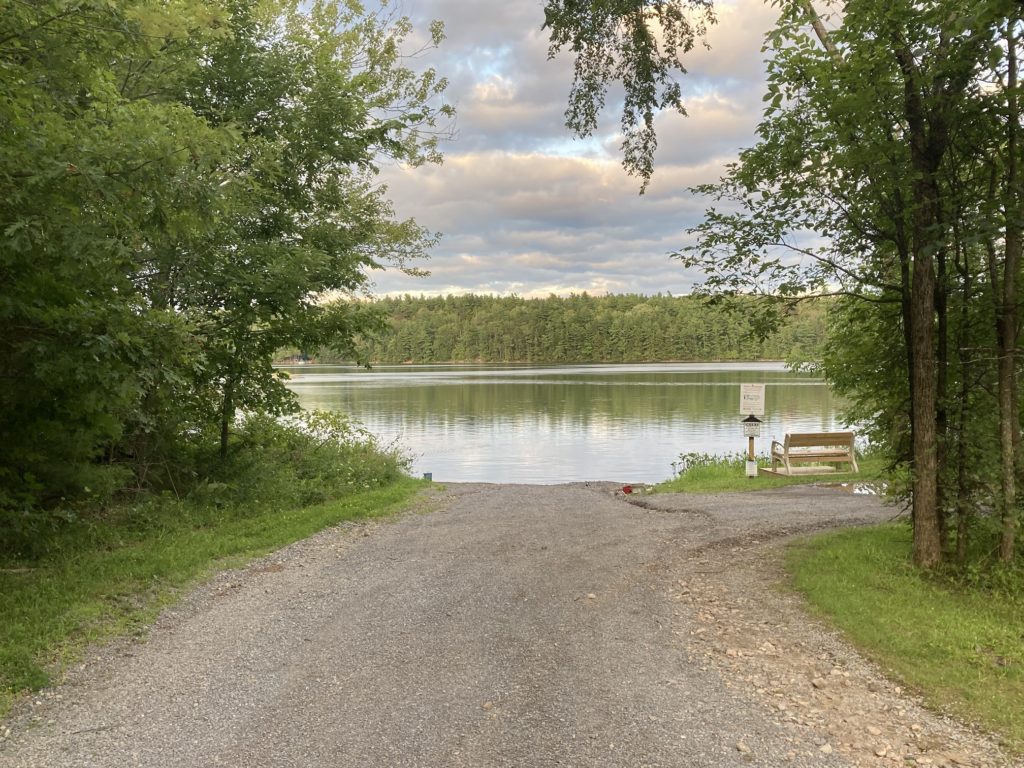 A view of the Lake of the Woods Fishing Public Access Site, the lake, and the wooden bench on a small wooden platform near the shore of the lake