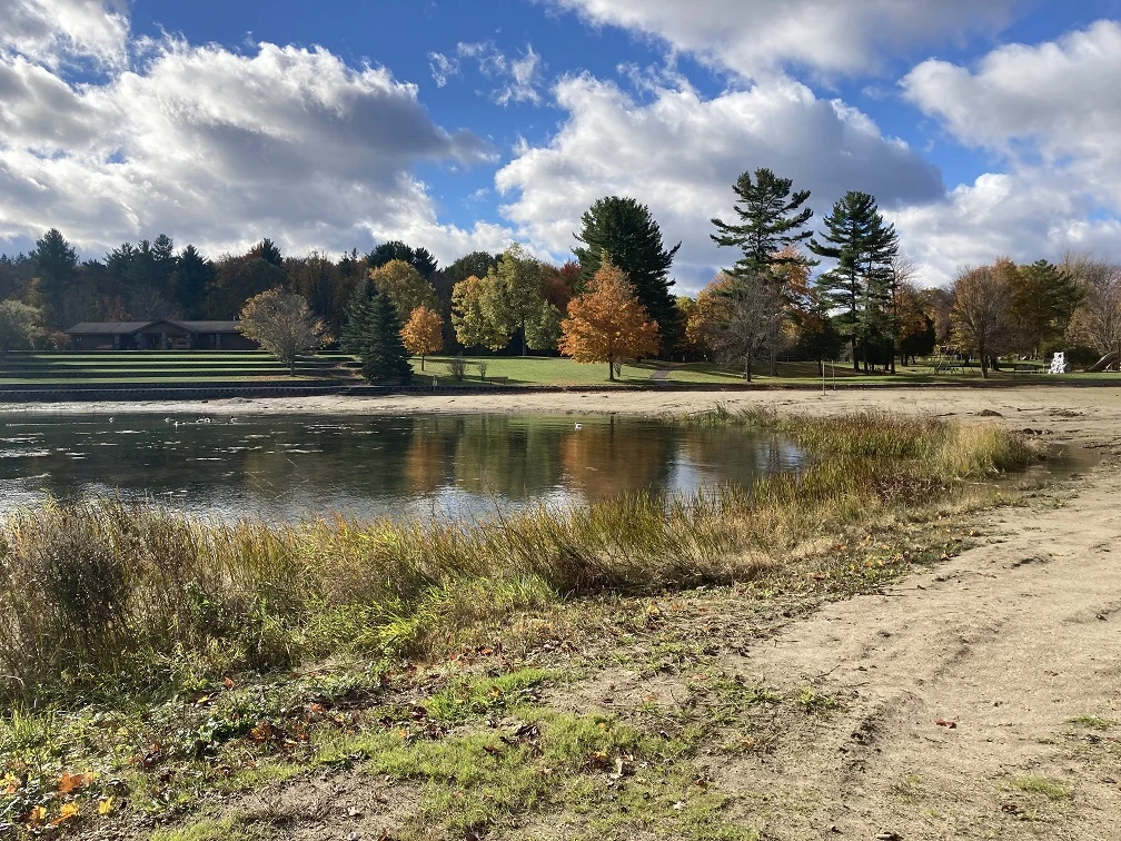 Photograph taken November 2021 of the beach at Jacques Cartier State Park.  Sandy and grassy areas along the shore of the river near the beach are shown.