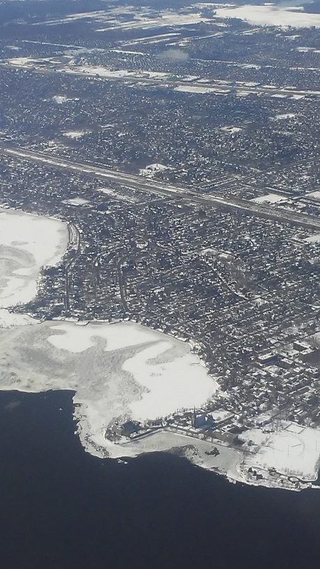 A photograph taken from an airplane of the St Lawrence River in Montreal, the ice is noticeable near the shore, but towards the middle of the river, the water is flowing and no ice is visible 