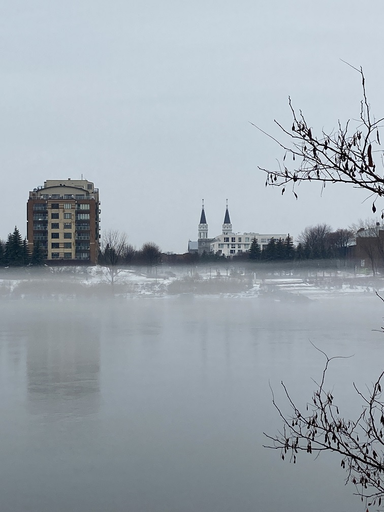 A photograph of a small portion of the river off Nuns Island in Montreal, the river is partially frozen, but you can still see a layer of water on top of the ice 